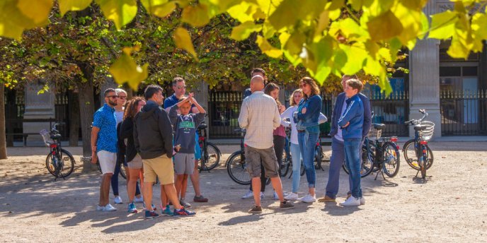 A group of cyclists on the Secrets of Paris, Off-the-Beaten-Path Bike Tour stop in the gardens of the Palais Royal