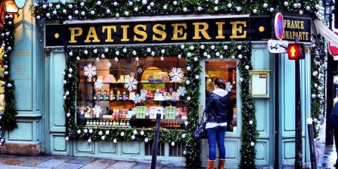 A patisserie storefront in Paris decorated for Christmas with baked goods and candy on display