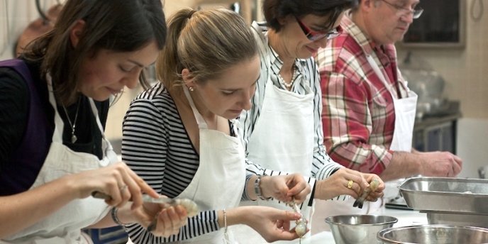 Four participatns in a Cooking Class In Paris clean shrimp for cooking