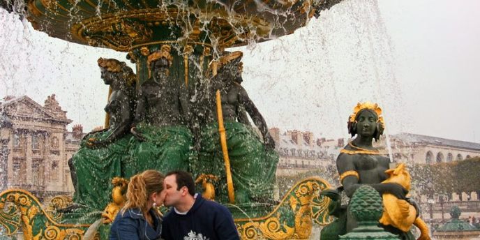 A couple kissing beneath a fountain at Place de la Concorde 