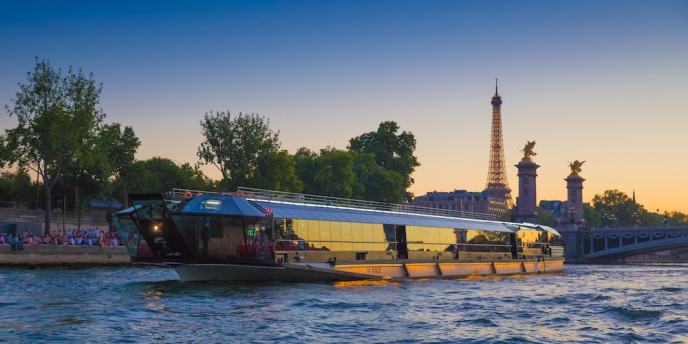 Bateaux Mouches dinner cruise at night passing under a Paris bridge with cthe Eiffel Tower in the background