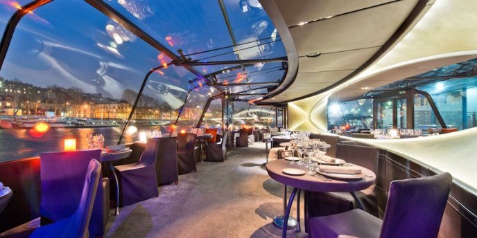 Photo of the interior of a glass-walled dinner boat during a Christmas Dinner Cruise on the Seine river in Paris