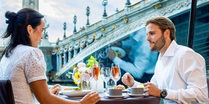 Couple enjoying a lunch cruise on the Seine River with views of Parisian bridges