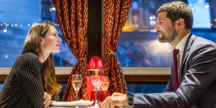 Couple dining on a Paris dinner cruise aboard Maxim's de Paris with elegant table setting