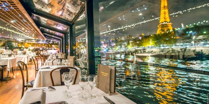 Interior of a Paris Seine dinner cruise boat at night with a view of the illuminated Eiffel Tower