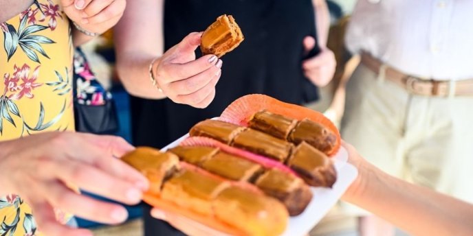 Photo of the hands of food lovers as they eagerly reach for samples during a Paris Chocolate & Pastry Tour