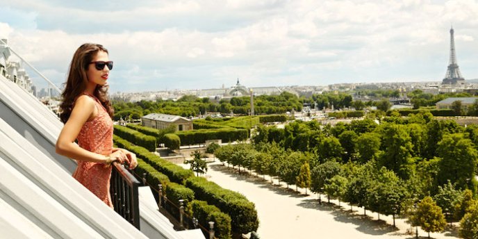 A woman guest at Hotel Meurice Paris viewes the Eiffel Tower from her room