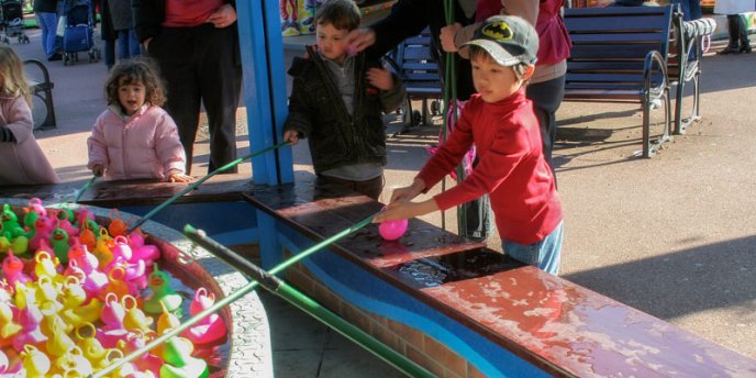 A young boy Fishing for plastic ducks at Jardin d'Acclimatation in Paris