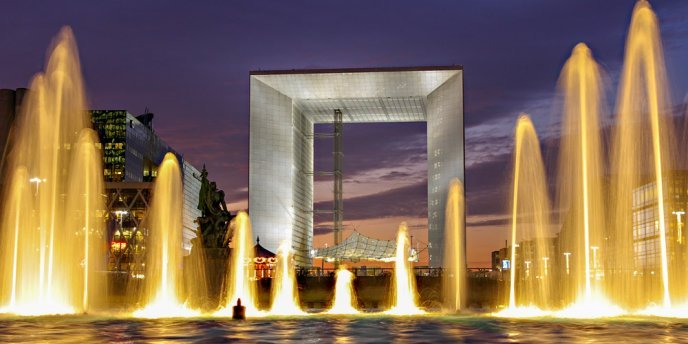 A lighted fountain in front of La Grande Arche at La Defense