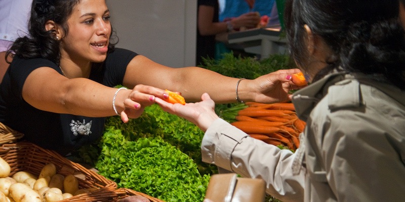 A vendor in a Paris market offers samples to shoppers