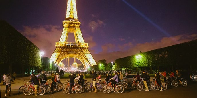 Cyclists stop at the base of the Eiffel Tower during a Paris Night Bike Tour