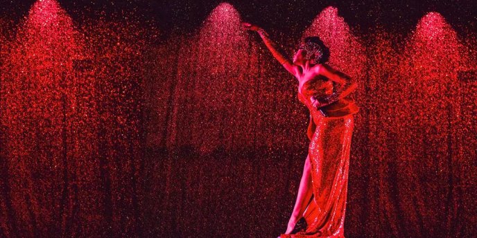 A solo dancer at Paradis Latin in Paris, against a red backdrop