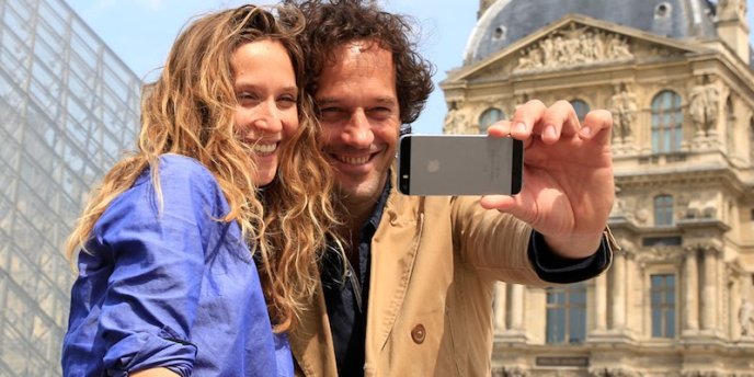 A couple in front of the Louvre taking a selfie