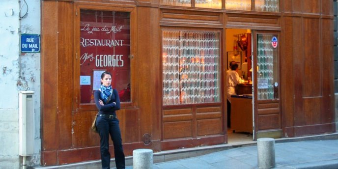 A woman waits outside restaurant Chez Georges in Paris