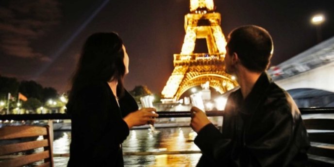 Couple on an evening champagnge cruise in Paris, with the Eiffel Tower