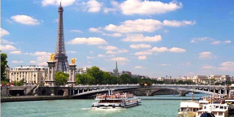 A sunny day in Paris with a boat on the Seine passing the Eiffel Tower