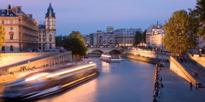 Boats crusing the Seine River at night, the Conciergerie is to the left