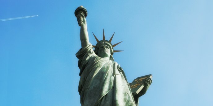 The Statue of Liberty on Allee des Cygnes in Paris with a blue sky and jet trail in the background