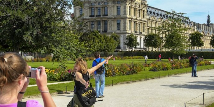 Visitors taking photos of themselves at Jardin des Tuileries in Fall with the Louvre in the background 