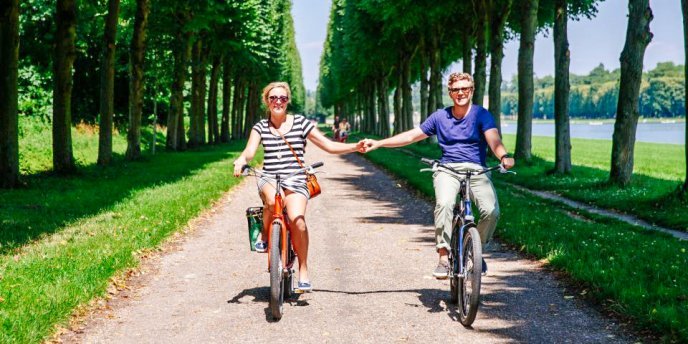 A couple holding hands on a bike tour through the gardens of Versailles