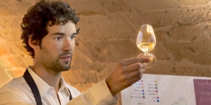 A Parisian sommelier holding a wine glass as he leads a wine tasting in Paris