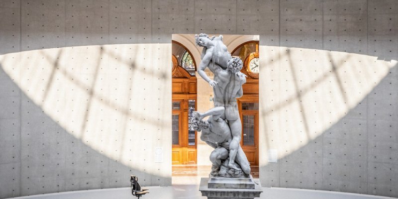 A statue at Bourse de Commerce lit by sunlight coming down from the glass down