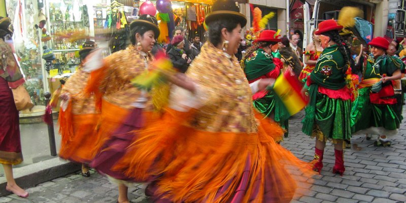 Carnaval de Paris paraders in orange skirts and bowler hats