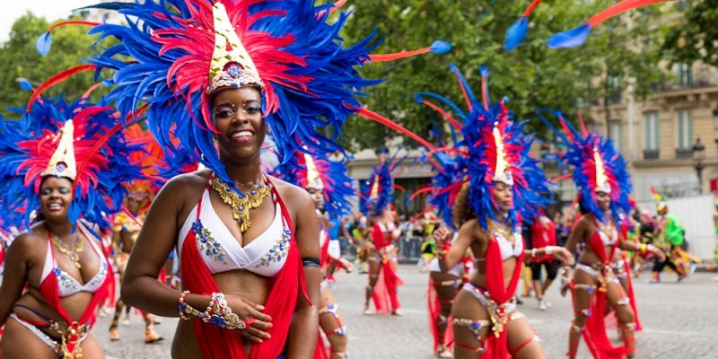 Carnaval de Paris parade dancers wearing red, white & blue, with feathered headdresses