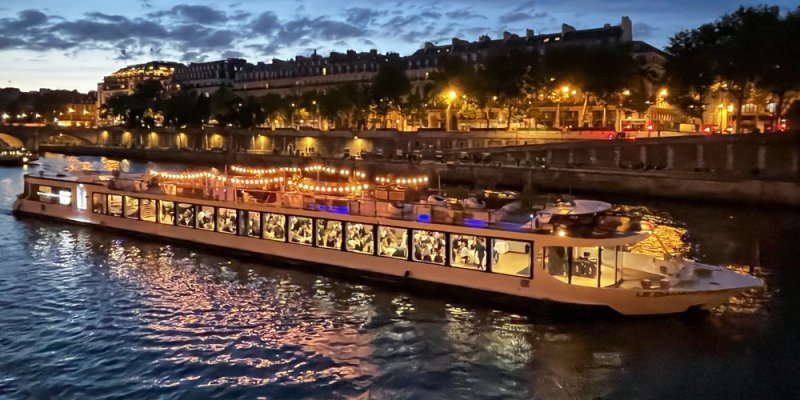 A dinner boat cruises the Sein River in Paris at night