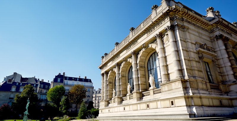 The palatial facade of Palais Galliera with arches, columns and three statues, overlooking its park