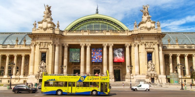 The facad of the Grand Palais in Paris with a tour bus driving by