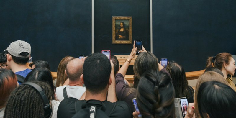 At the Louvre a crowd in front of the Mona Lisa, everyone taking photos