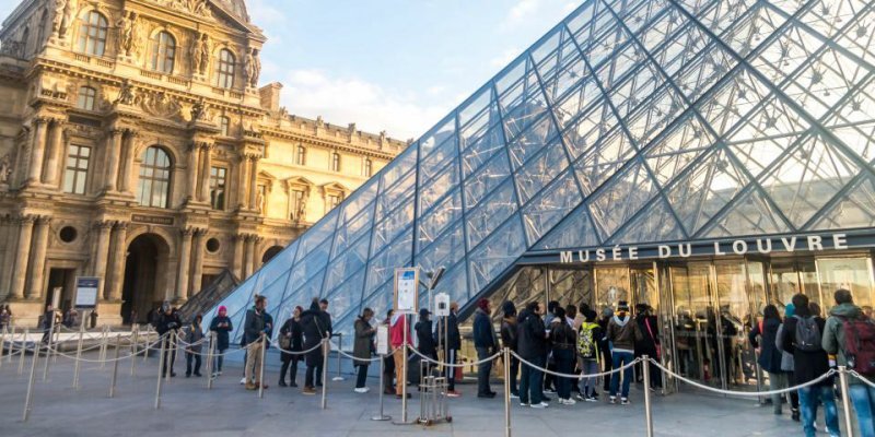 Visitors in line outside the Louvre Pyramid waiting to get in