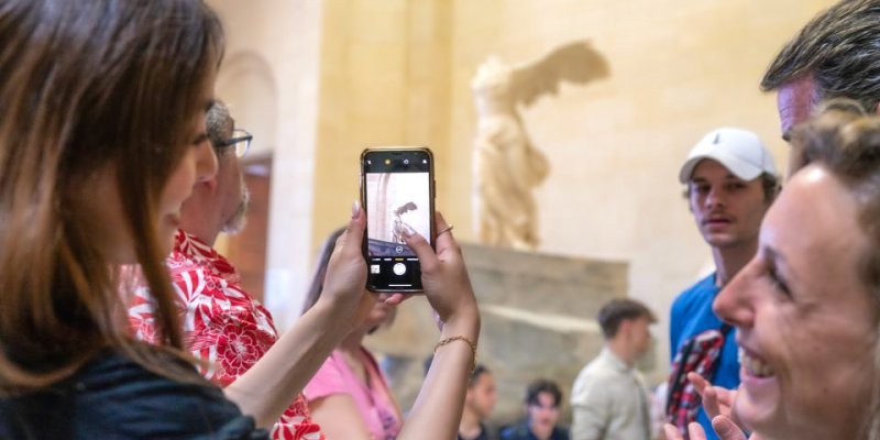 A visitor takes a phot of the Nike of Samothrace at the Louvre