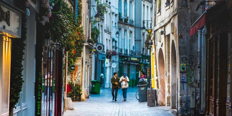 Two visitors walk along the cobblestone streets of the historic Marais Paris 