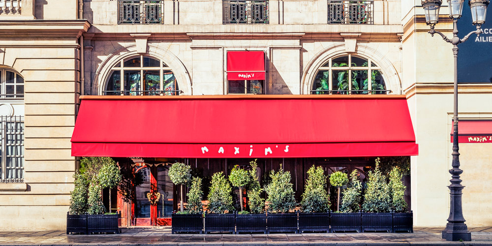 A bright red awning highlights the exterior of Maxim's Paris