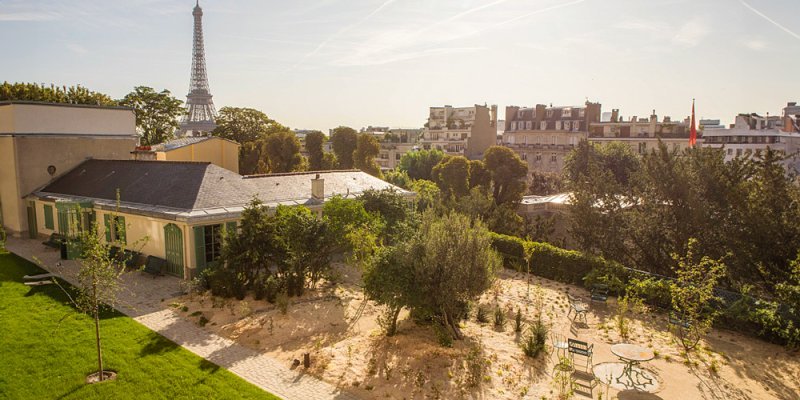 Aerial view of Maison de Balzace, surrounded by greenery, with the Eiffel Tower in the distance