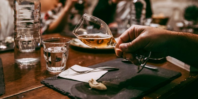 A hand holds a wine glass during a cheese & wine tasting tour