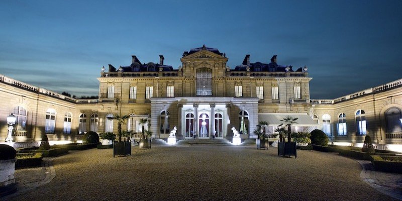 The courtyard and wings of Musee Jacquemart Andre, lit at night. There are palm trees!