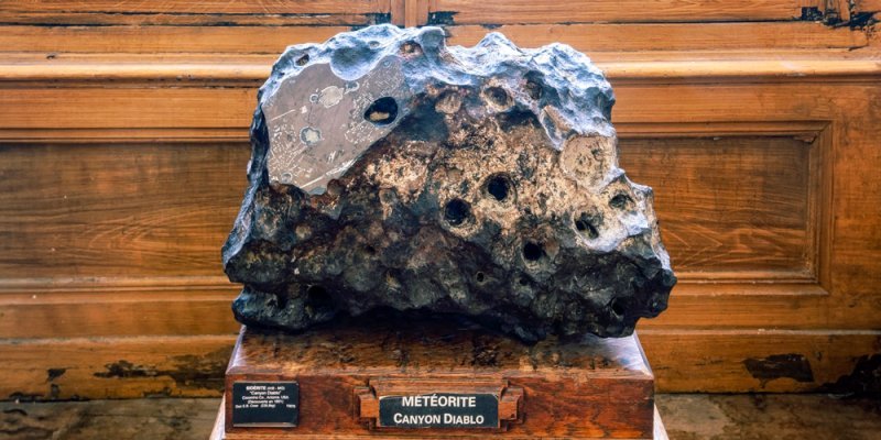 A jaggec black meteorite, pockmarked with space holes, on display at the Paris Mineralogy Museum