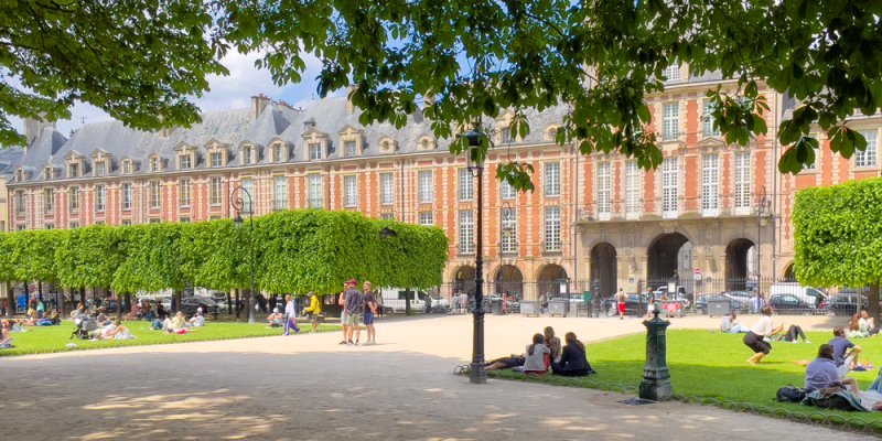 People relaxing on the grass at Places des Vosges on a sunny day