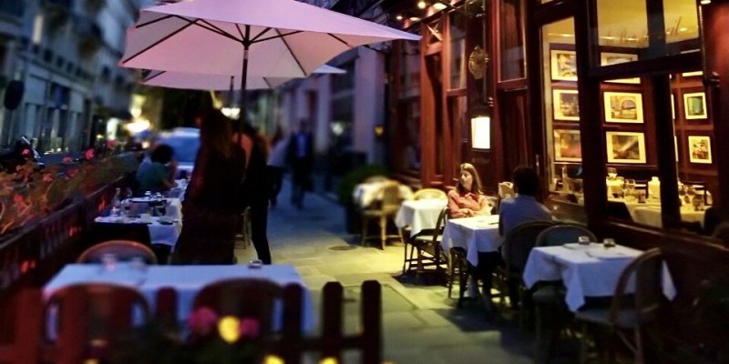 A table of two diners softly lit by the windows of restaurant Au Bon Accueil