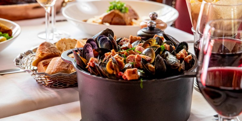 A large pot of mussels and other seafood on the table at Au Pied de Cochon