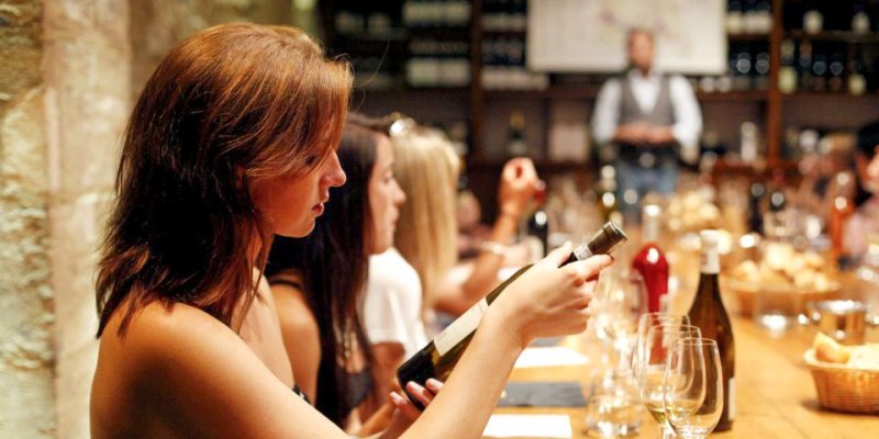 Visitors sitting at a long table participate in Food & Wine tasting in a Paris wine cellar