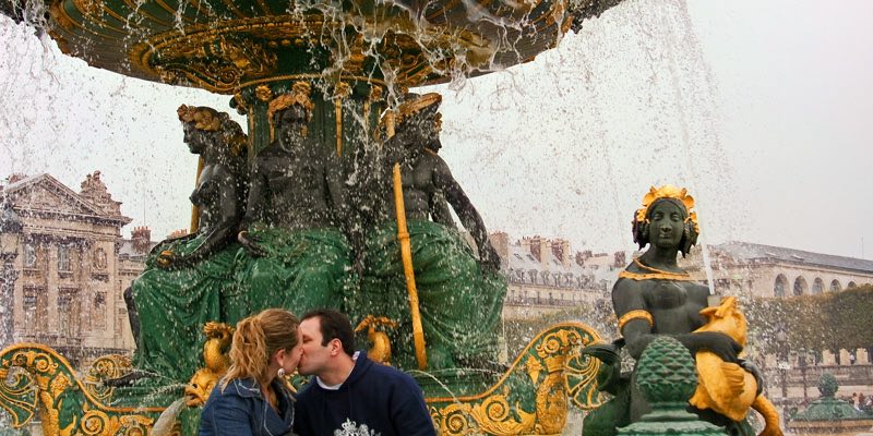 A couple kissing beneath a fountain at Place de la Concorde 