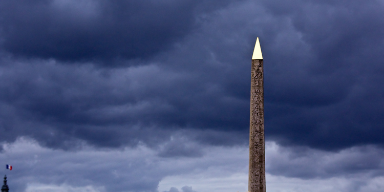 The Obelisk on Place de la Concorde in Paris, with a dark blue cloudy sky behind